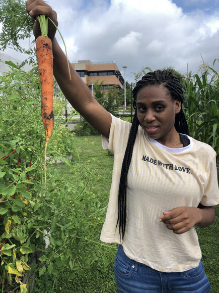 Female student holds up a large carrot