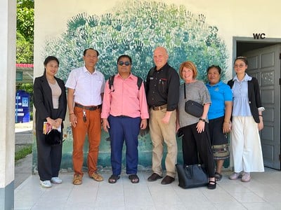 A teacher stands with her students on a photo backdrop cloth.