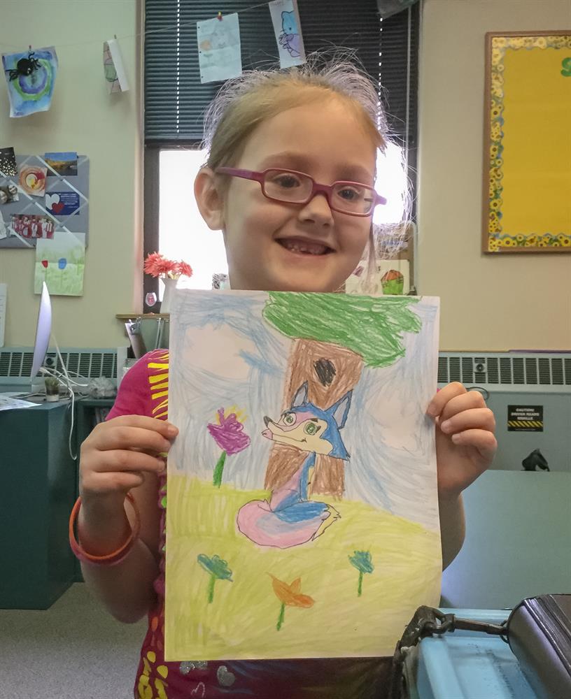 Student holds an illustration of Fiona the Fox's Momma Fox